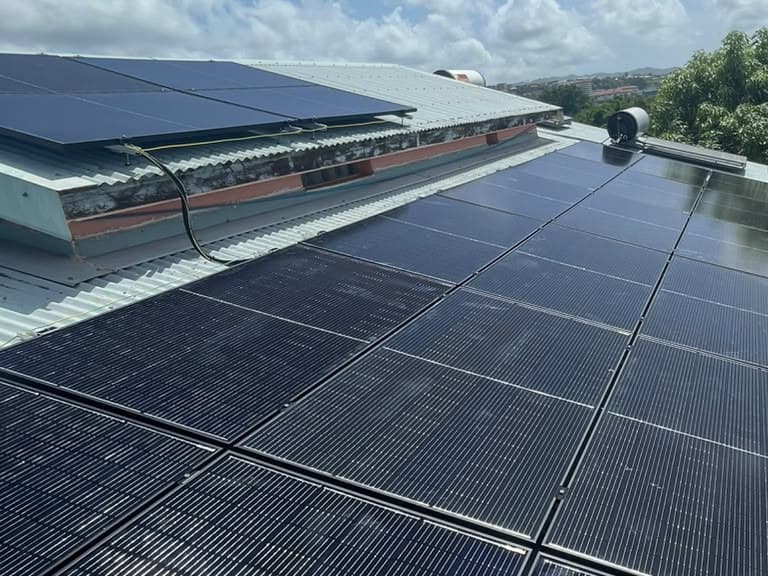 Rangées de panneaux noirs sur un toit de tôle bleu-vert, Martinique
